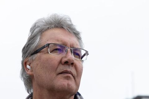 Contemplative senior man looking up wearing glasses and wireless earbud outdoors