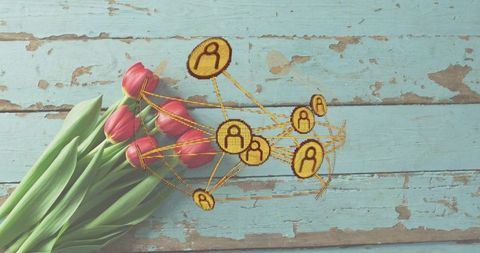 Laying pink tulip bouquet with gold embroidered connection network on turquoise wood planks