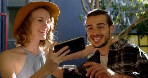 Friends Smiling and Taking Selfie Outdoors in Sunlight