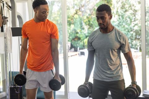 African american men lifting dumbbells in bright home gym partner workout