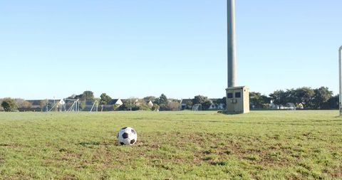 Soccer Ball on Suburban Field Near Goalpost and Light Pole