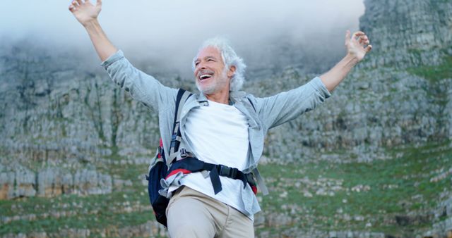 Caucasian man celebrates success outdoor, with copy space. His joy reflects the exhilaration of achieving a hiking milestone.