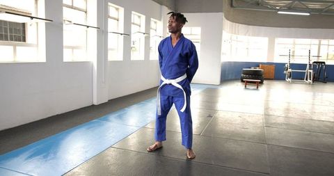 Man Practicing Martial Arts on Mats in Gym with Blue Gi