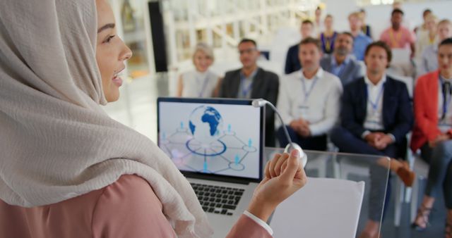 A young Asian businesswoman in a hijab speaks and gestures at a conference, receiving applause. - Download Free Stock Photos Pikwizard.com