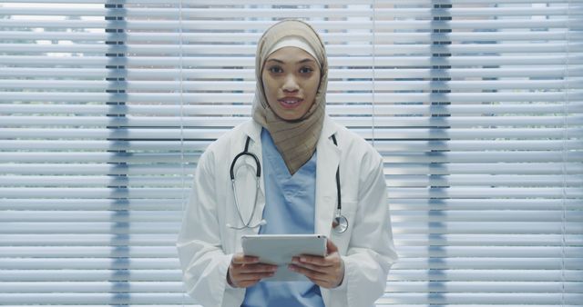 Female Doctor in Hijab Holding Digital Tablet in Medical Office - Download Free Stock Images Pikwizard.com