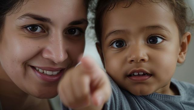 Smiling woman and toddler pointing together closeup, family bonding caregiver connection
