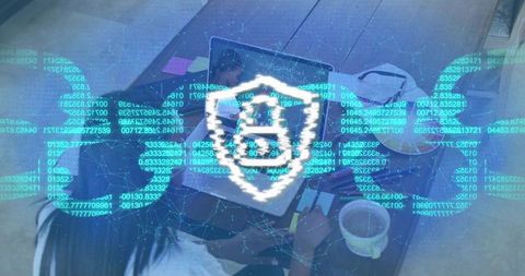 Two Women Collaborating on Laptop and Notebook with Cybersecurity Shield Overlay