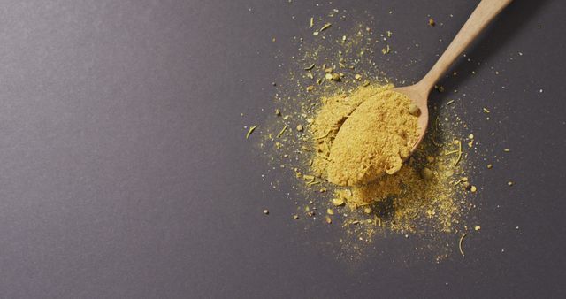 Image of spoon with tumeric seasoning lying on grey surface. cooking, seasonings, spices, taste and flavour concept.