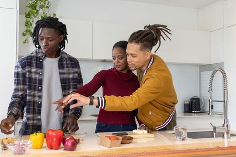 African american friends cooking at modern kitchen island chopping fresh vegetables