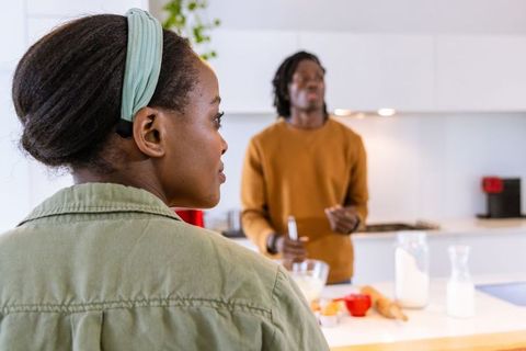 African american couple cooking together in modern bright kitchen, man stirring batter
