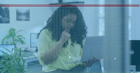 Woman holding laptop studying code in modern office with thoughtful pose and plants