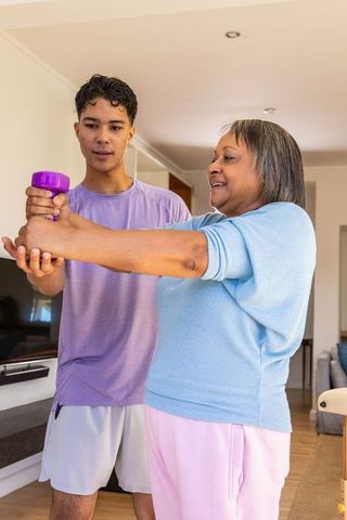 Senior woman engaged in fitness training at home with personal coach guidance