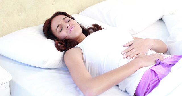 Woman Experiencing Abdominal Pain While Lying in Bed - Download Free Stock Images Pikwizard.com