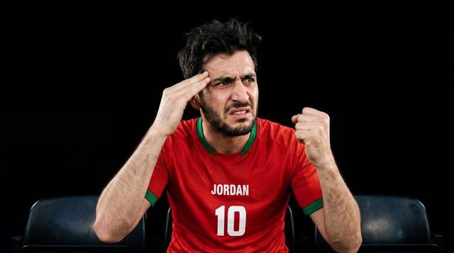 Frustrated fan wearing jordan 10 jersey clenching fist and holding temple in stadium