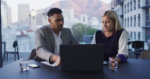 Colleagues Discussing Project on Laptop in Modern Office