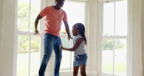 Father and daughter playtime near home windows in bright interior