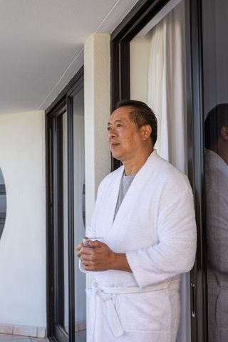 Mature man in bathrobe enjoying tranquil balcony moment