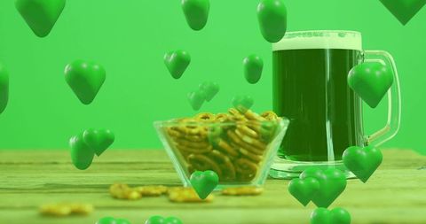 Emerald st. Patrick's beer with pretzels and floating hearts on rustic wooden table