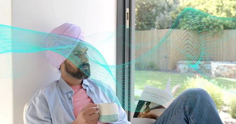 Relaxing indian man reading in sunlit nook with pink turban mint mug and turquoise wave