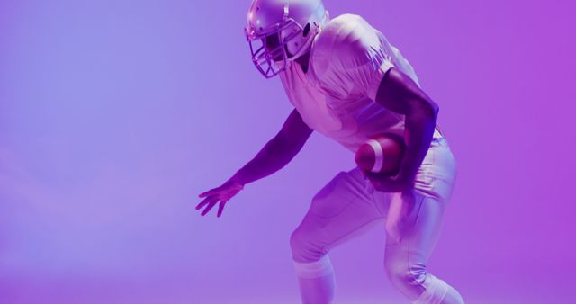American football player wearing a helmet and uniform posing while holding a football in dynamic neon light. Can use for sports event promotions, football team posters, athlete training campaigns, modern energetic designs.