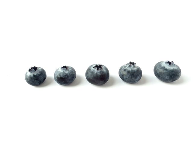 This image shows five fresh blueberries lined up against a white background. Perfect for use in advertisements focusing on health and nutrition, recipes involving berries, or minimalist designs highlighting natural and fresh produce.