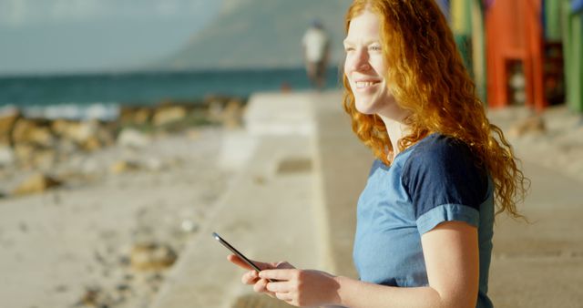 Smiling Redhead Woman Using Smartphone at Beach on Sunny Day - Download Free Stock Images Pikwizard.com