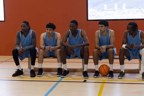 Male Basketball Team Sitting on Bench in Gym