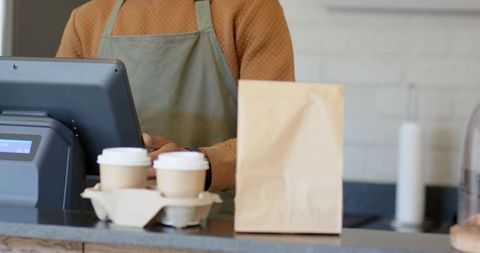 African american barista serving takeaway coffee, packing order on minimalist cafe counter
