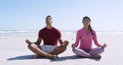 Couple Practicing Beach Meditation in Athletic Wear for Mindfulness and Wellness