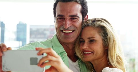 Smiling Couple Captures Joyful Moment with Smartphone Selfie
