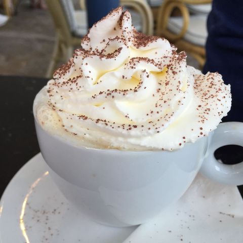 Hot chocolate with whipped cream and cocoa sprinkles in white mug
