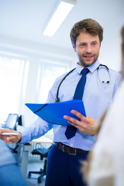 Doctor discussing patient's condition while holding a clipboard. Ideal for healthcare, medical consultations, professional health services, patient care articles, and hospital-related content.