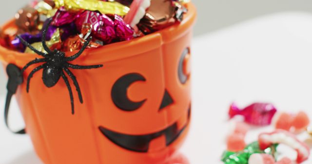 Scary halloween pumpkin printed bucket full of candies against grey background. halloween holiday and celebration concept