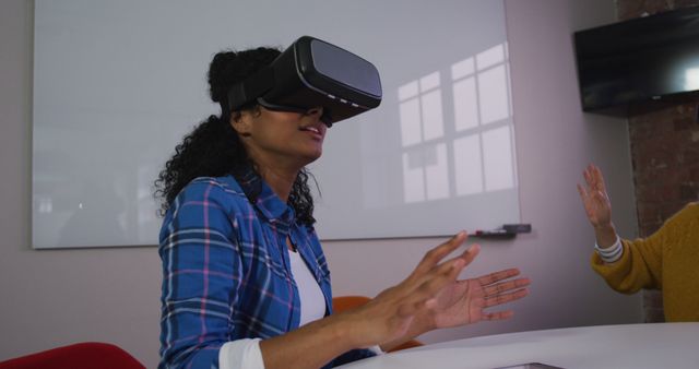 Young woman experiencing virtual reality at work, demonstrating the integration of technology in modern workspaces. Ideal for use in articles or presentations about VR technology, workplace innovation, or tech industry trends.