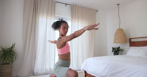 African American Woman Practicing Warrior Pose in Bedroom