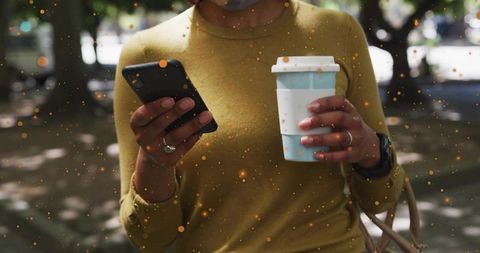 Woman Walking in Park Holding Smartphone and Coffee Cup Wearing Mustard Top Urban Lifestyle