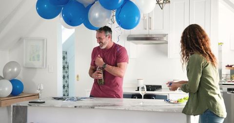 Couple Tidying Up After Birthday Celebration with Balloons in Kitchen