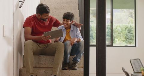 Father and Son Bonding with Tablet Technology on Home Stairs
