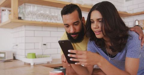 Couple Relaxing at Home with Smartphone in Kitchen