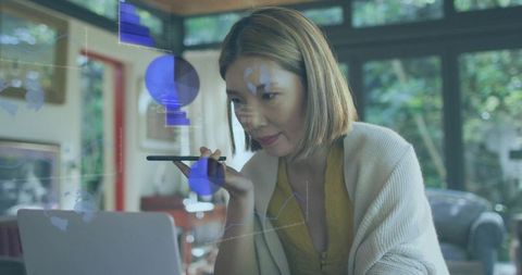 Remote professional using stylus and laptop with floating data overlays in home workspace