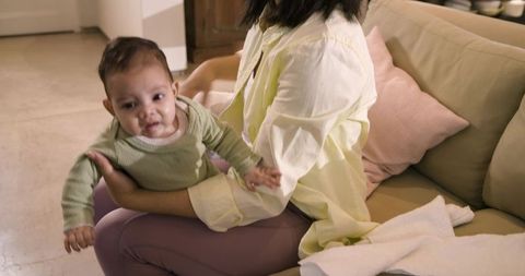 Affectionate mother holding happy infant at home