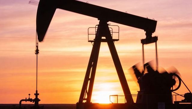 Pumpjack silhouetting at sunset pumping oil in rural field for energy industry visual