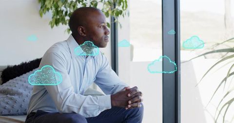 Professional man gazing through window with teal cloud overlays for cloud computing ideas