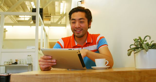 Young Man Reading Tablet While Drinking Coffee in Modern Café - Download Free Stock Images Pikwizard.com