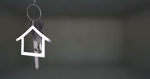 Hanging house keychain with multiple keys on metal ring against dark blurred gradient background