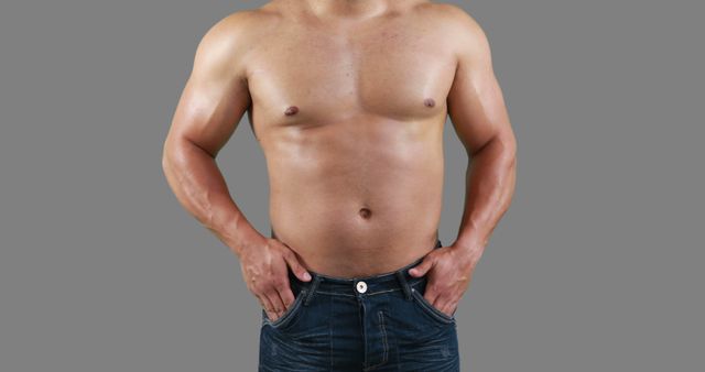 A shirtless Caucasian man showcases his fit physique, with copy space. His hands are placed on his hips, emphasizing his toned abdominal muscles and upper body strength.
