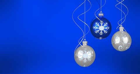 Festive christmas baubles against vibrant blue background