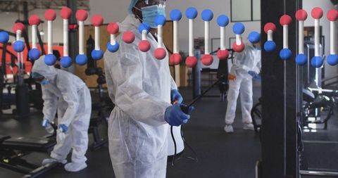 Sanitation workers in protective gear disinfecting gym environment