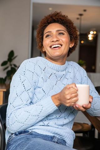 Smiling Woman Holding Mug in Modern Kitchen Enjoying Relaxation