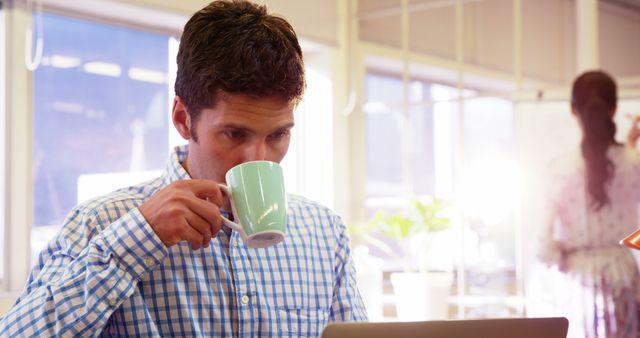 Young Professional Drinking Coffee while Working on Laptop in Modern Office - Download Free Stock Images Pikwizard.com